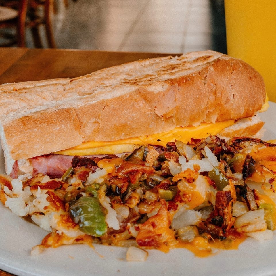 Mamas Kitchen's breakfast sandwich with ham, egg, and cheese, served with a side of home fries.